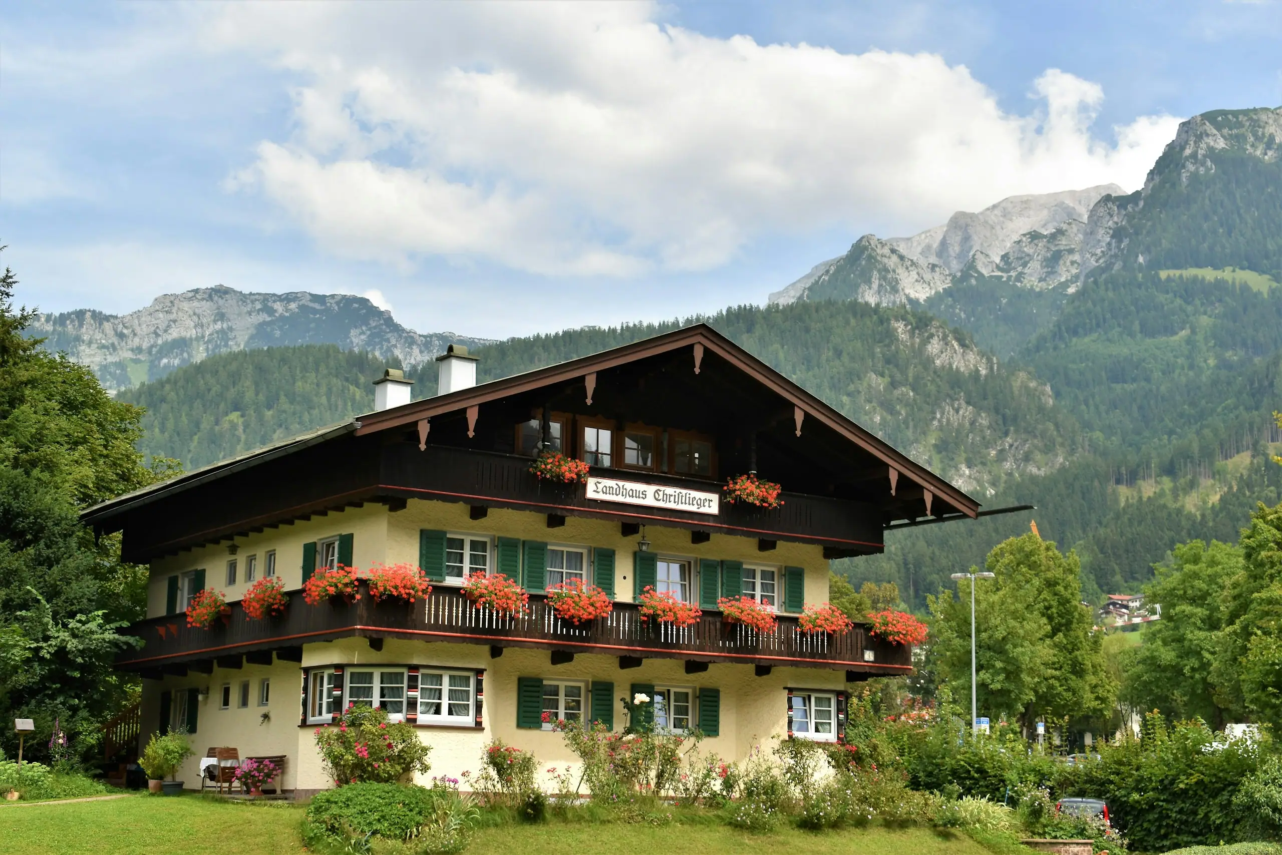 Oberbayerisches Wohnhaus mit Holzbalkon und Blumenkästen vor Bergkulisse