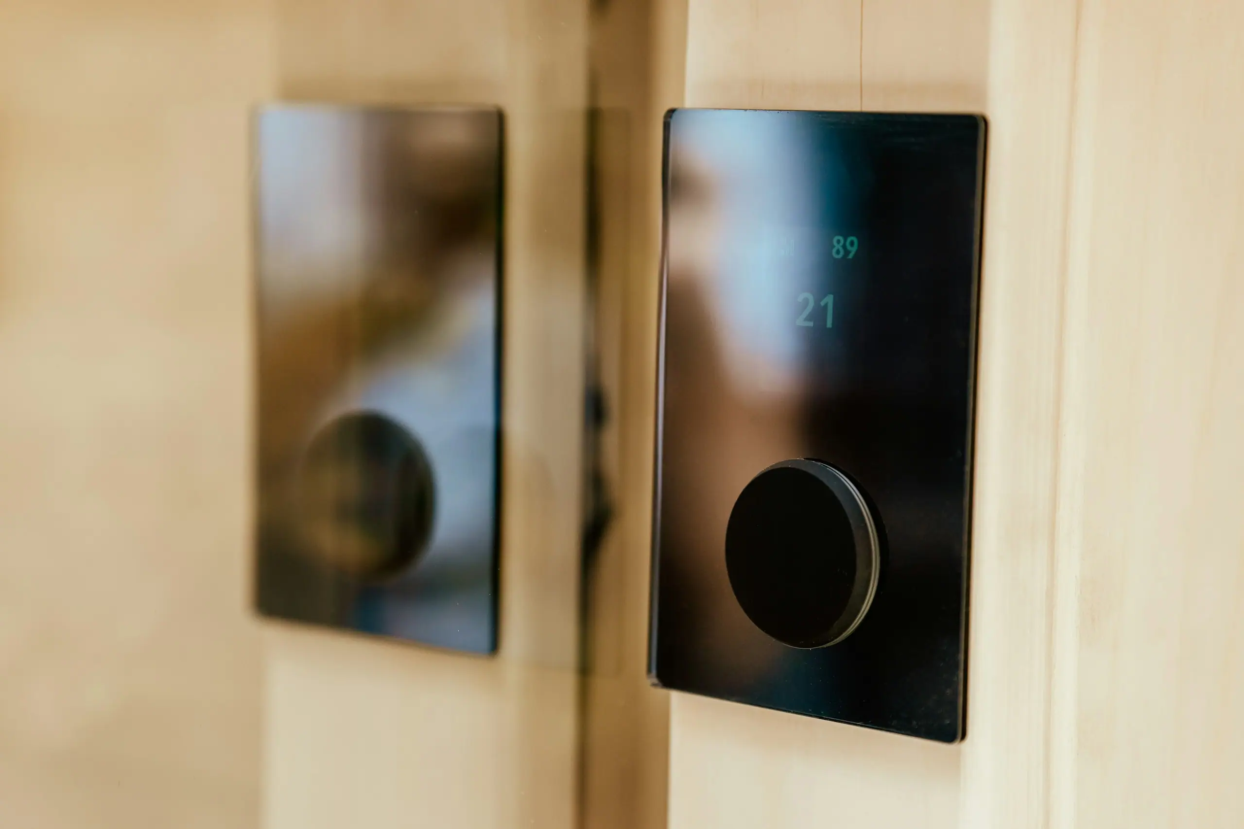 Zwei flache, schwarze Bedienpanels an einer Holzwand